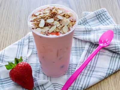 A delicuise yogurt with strawberries, almonds and banana.
